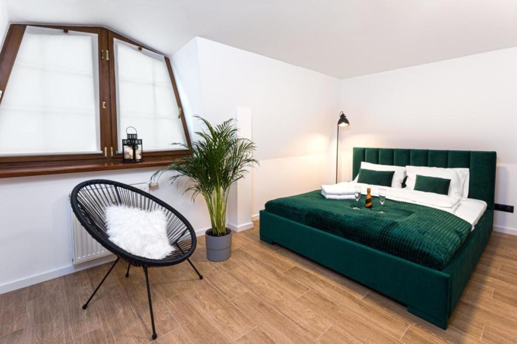 um quarto com uma cama verde e uma cadeira em Apartament Bianco Verde em Czestochowa