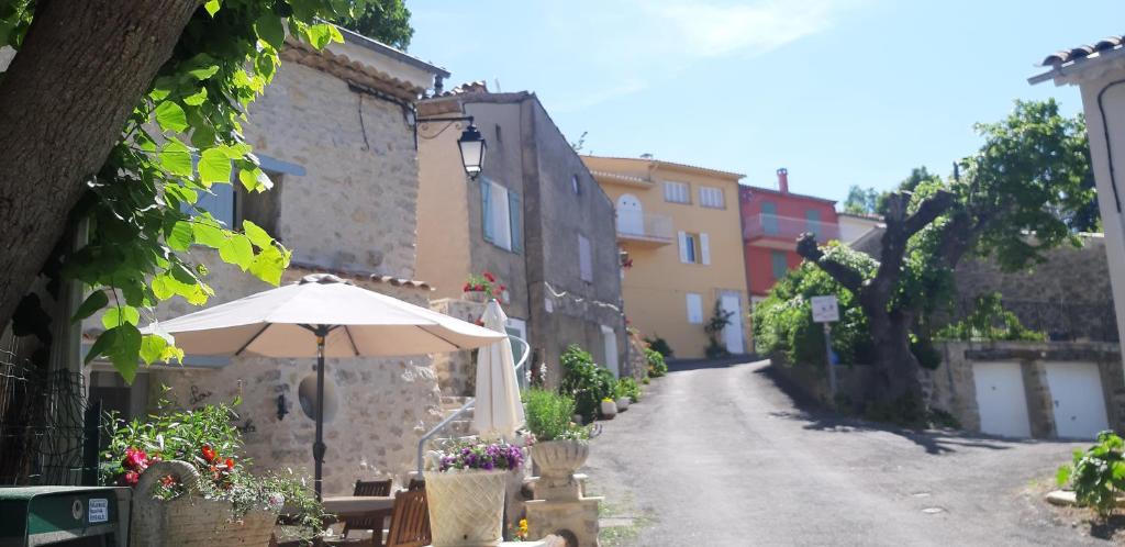 a street with an umbrella and a table and chairs at Studio tout confort dans maison de caractère in La Bastide