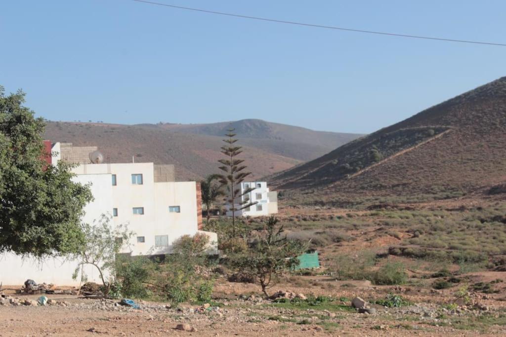 a white building in the middle of a field at Asunfou : Appartement d'apaisement in Mirleft