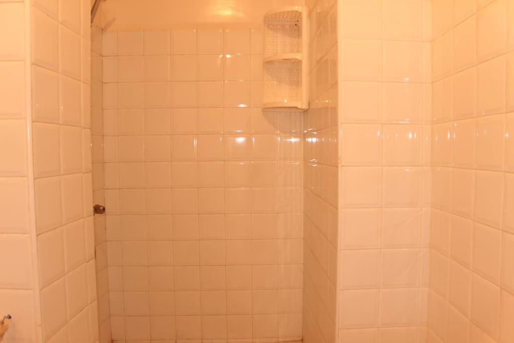 a bathroom with a shower with white tiles at Asunfou : Appartement d'apaisement in Mirleft