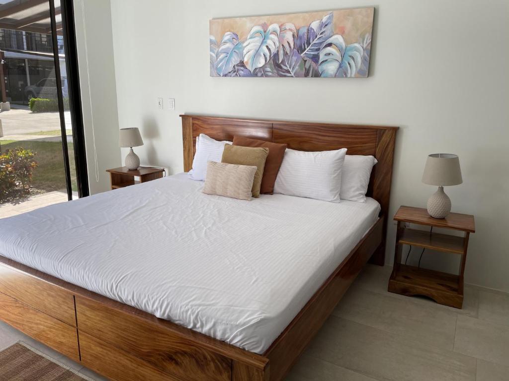 a bedroom with a large bed with white sheets and pillows at Perfect combination between nature and fun in Jacó