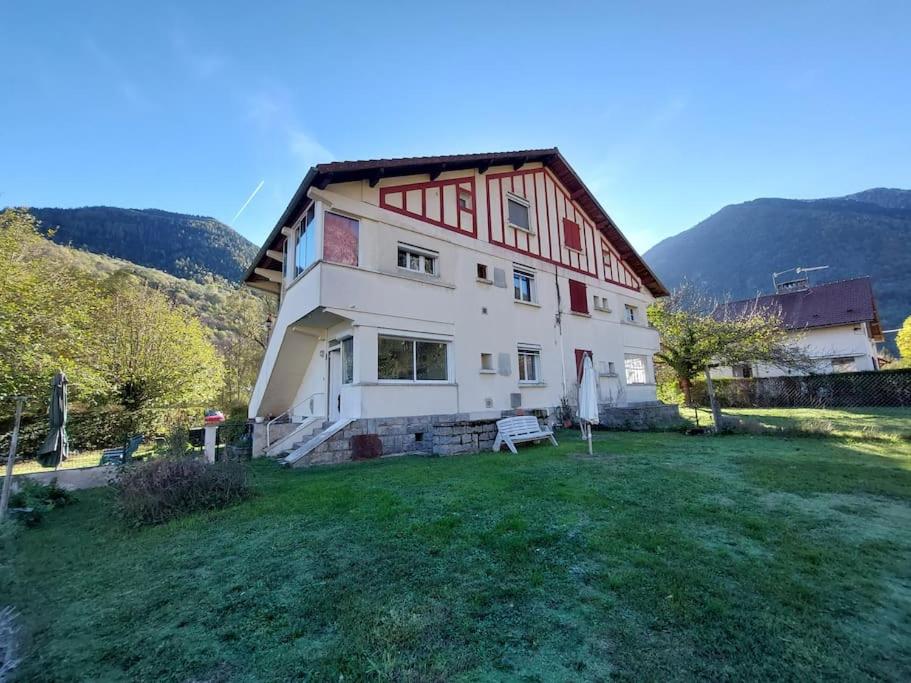une grande maison avec une cour en gazon devant elle dans l'établissement Beau jardin proche randonnée ski calme plain pied, à Auzat