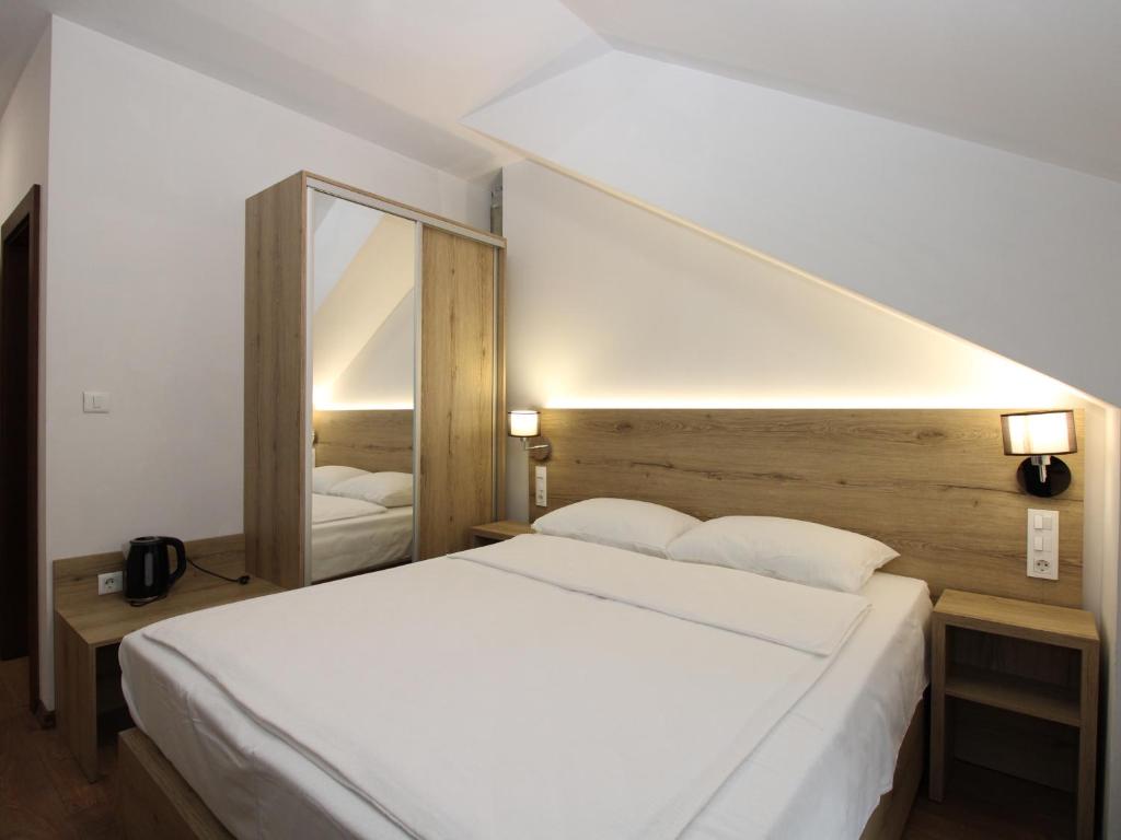 een slaapkamer met een wit bed en een grote spiegel bij Vila Alexandra in Sarajevo