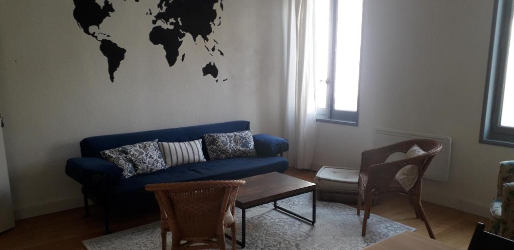 - un salon avec un canapé bleu et une carte du monde sur le mur dans l'établissement Appartement cosy au coeur du centre historique., à Arles