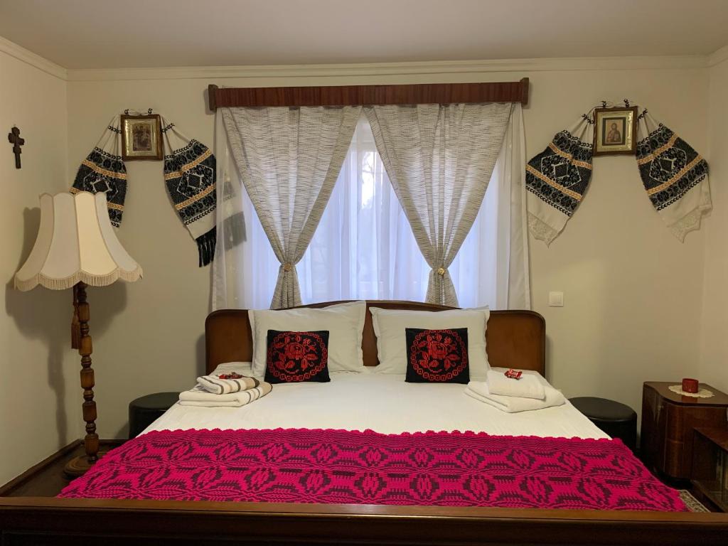 a bedroom with a bed with red sheets and a window at CASA LUI MOȘU in Alba Iulia