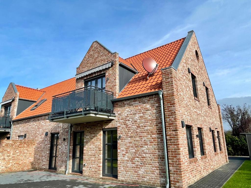 ein Backsteingebäude mit Balkon darüber in der Unterkunft Backbord Greetsiel in Krummhörn