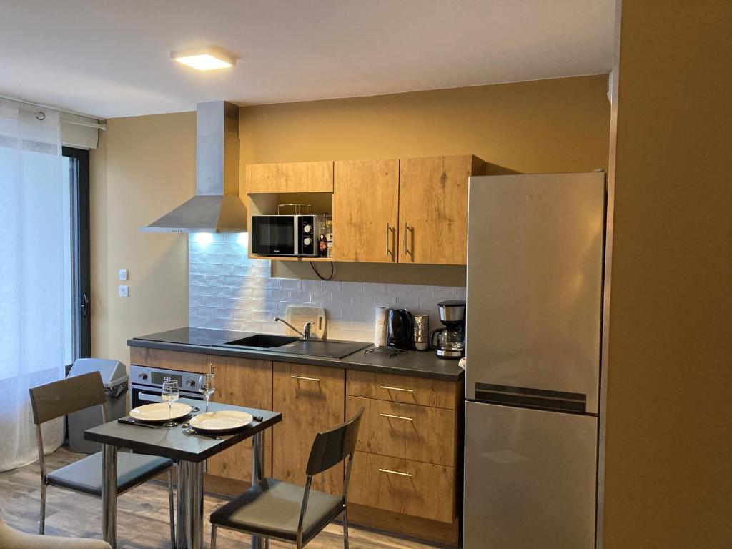 a kitchen with a table and a stainless steel refrigerator at Le Petit Fabre in La Roche-sur-Yon