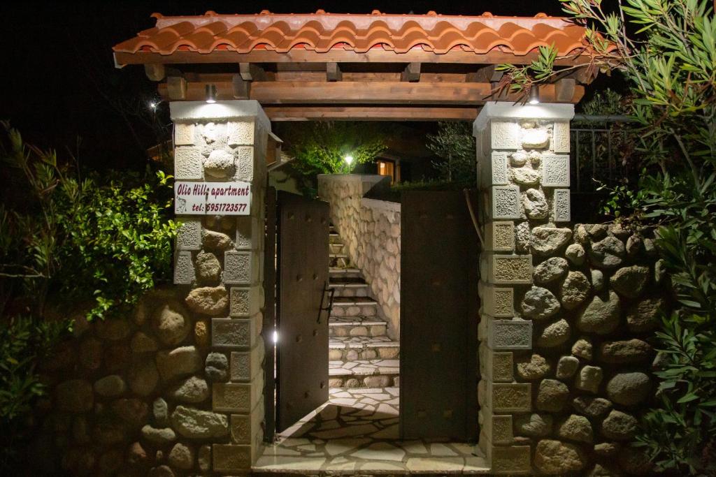 a gate to a house at night with a sign at Meteora Olio Hills apartment in Kalabaka