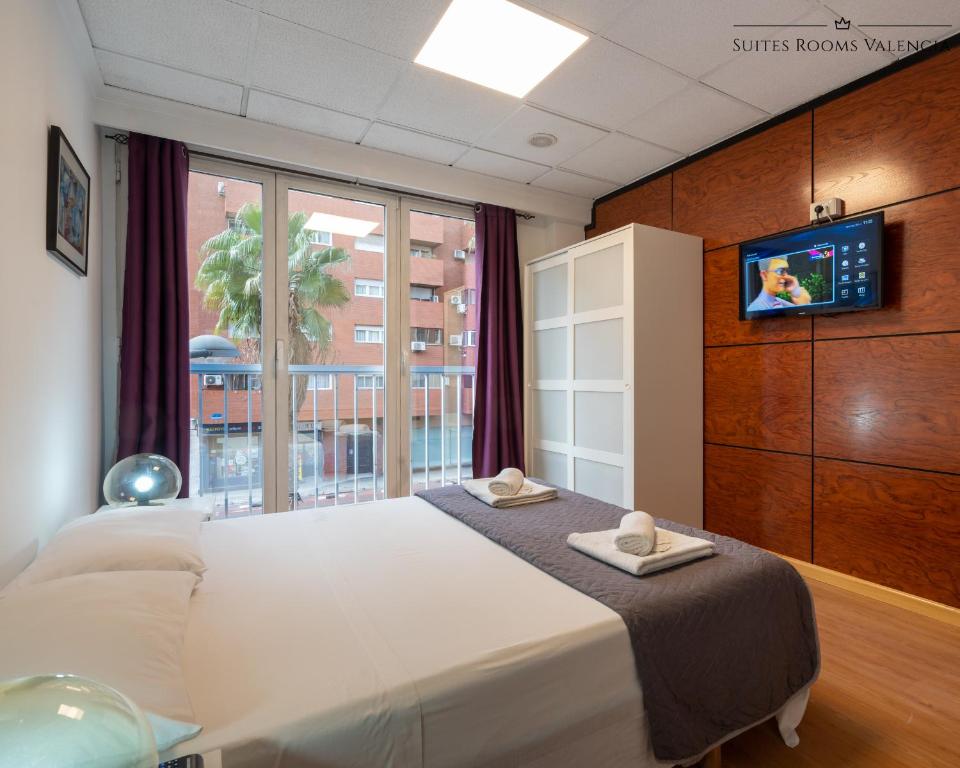 a bedroom with a bed with a tv and a window at Suites Rooms Valencia in Valencia