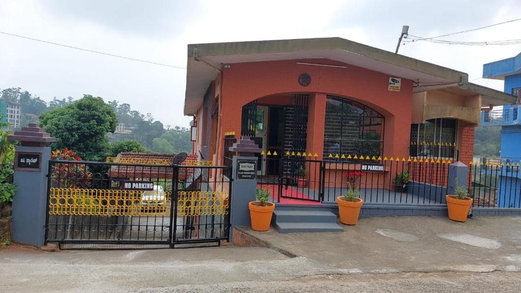 a building with a gate with plants in front of it at Honey Palace Homestay in Madikeri