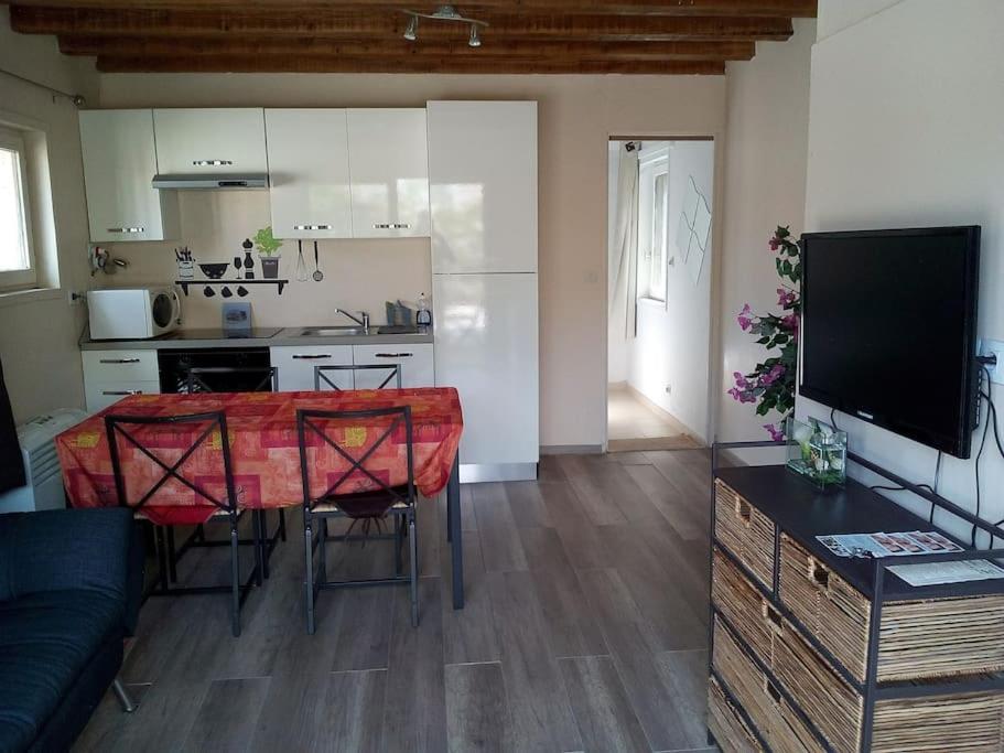 a living room with a table and a kitchen at Single storey 40m² bordering pine forest and spa in Noves