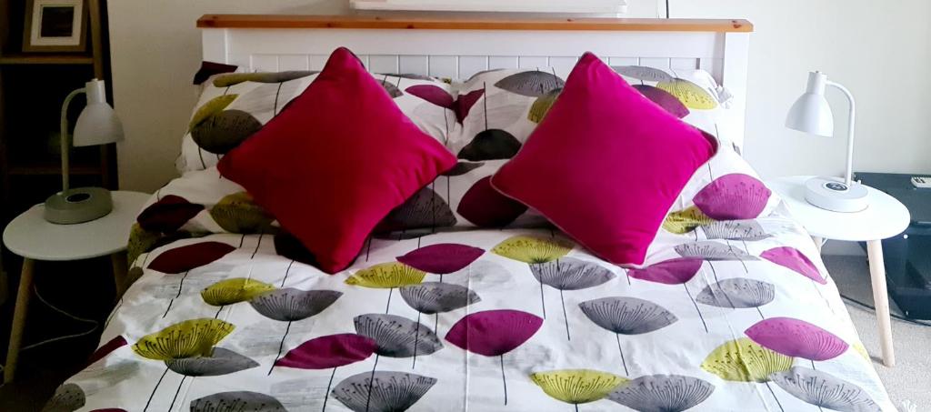 Una cama con muchas almohadas de colores. en Charming Kintbury Cottage en Kintbury