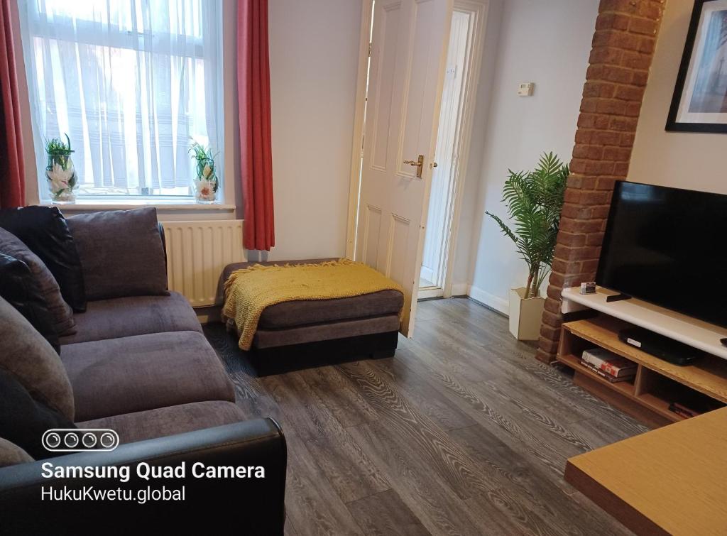 uma sala de estar com um sofá e uma televisão em Salisbury House-Huku Kwetu Spacious 4 Bedrooms House- Sleeps 6 - Luton Town Centre em Luton