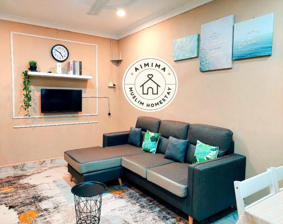 Aimima Muslim Homestay @ Lost World Of Tambun. في Kampong Batu Lapan: غرفة معيشة مع أريكة وساعة على الحائط