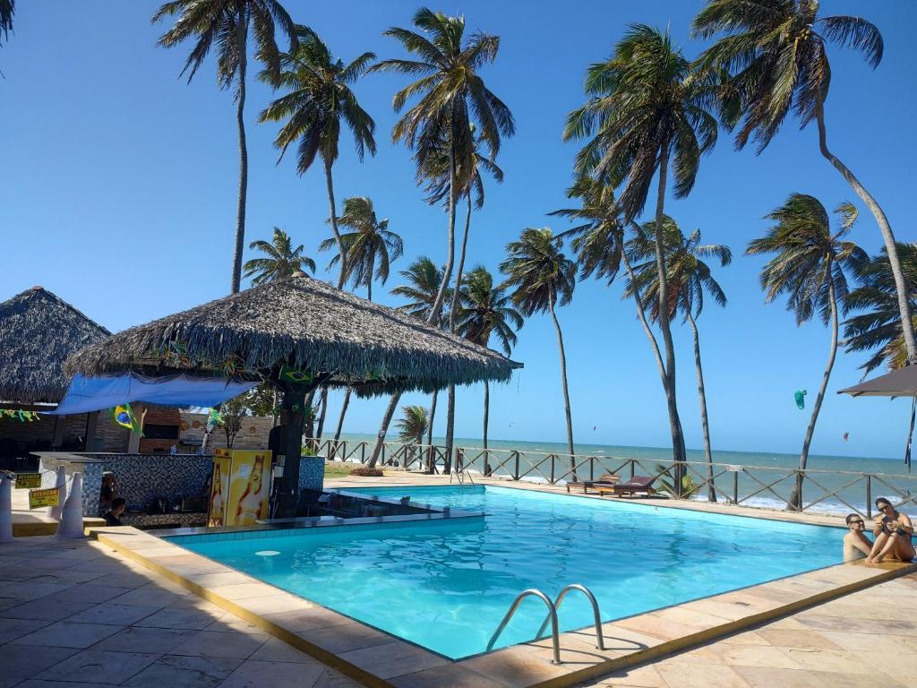 uma piscina com palmeiras e praia em Eco Paradise Temporada Aconchegante - Joana Vasconcelos em Cumbuco