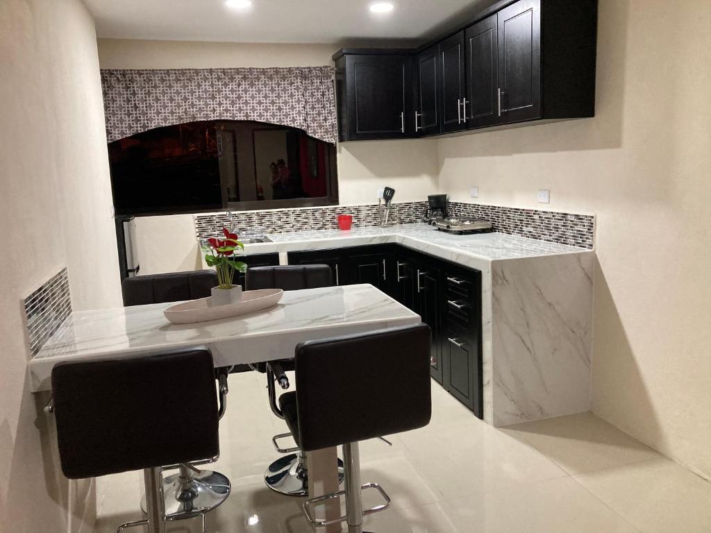 a kitchen with a white counter and black cabinets at Hospedaje Ana Lu, Only 10 minutes from airport in Alajuela City