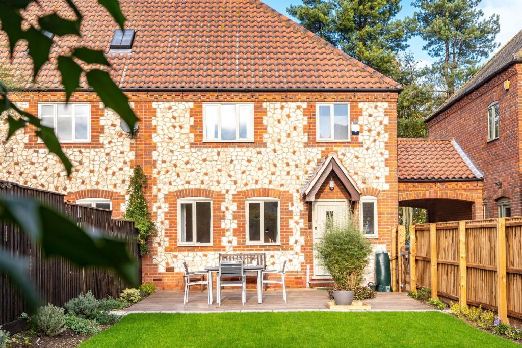 a brick house with a table and chairs in the yard at Staithe View by Big Skies Cottages in Burnham Deepdale