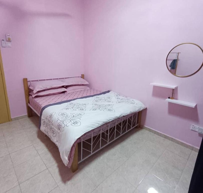 een bed in een witte kamer met een spiegel bij NuReezal Homestay Seremban in Seremban