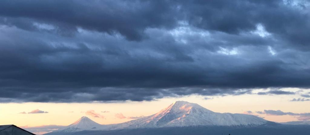 een uitzicht op een berg onder een bewolkte hemel bij Glide Hostel in Jerevan