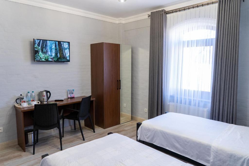 ein Hotelzimmer mit einem Schreibtisch, einem Bett und einem Tisch in der Unterkunft NEST INN in Taschkent