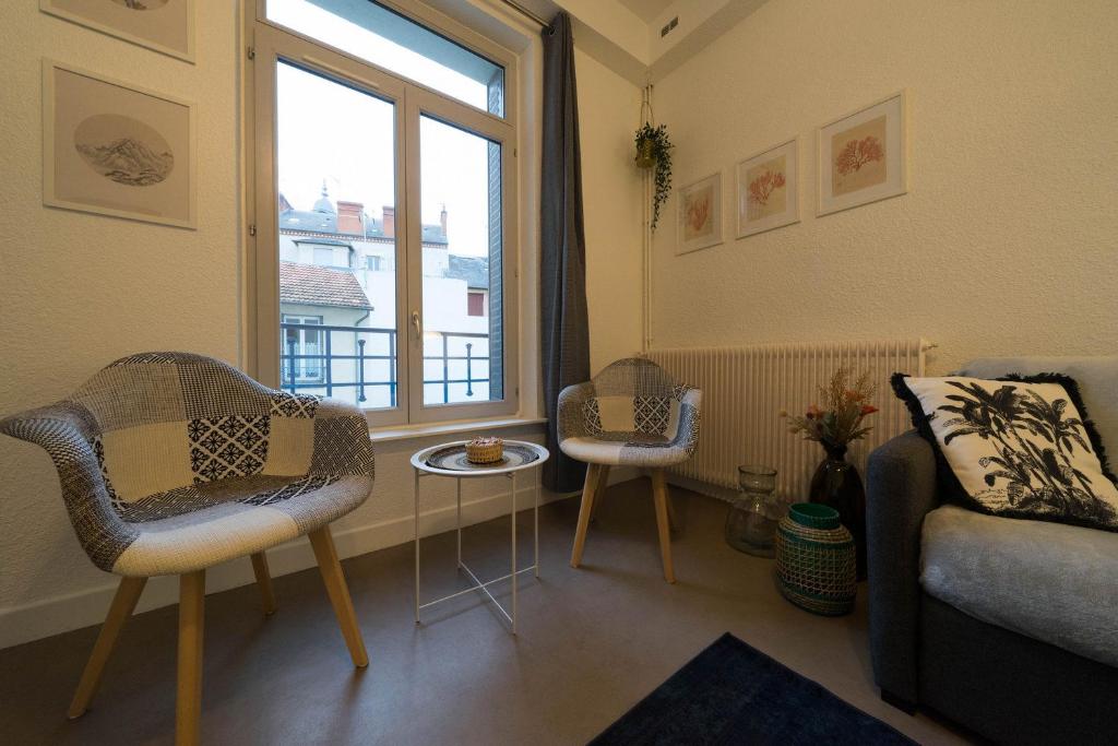ein Wohnzimmer mit einem Sofa und einem Fenster in der Unterkunft AppartUnique - Chez Klein in Vichy