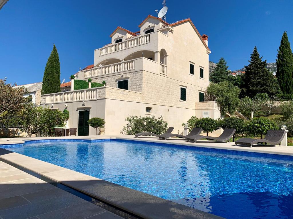 une maison avec une piscine en face d'un bâtiment dans l'établissement Apartments Villa Jadranka Adults only, à Bol