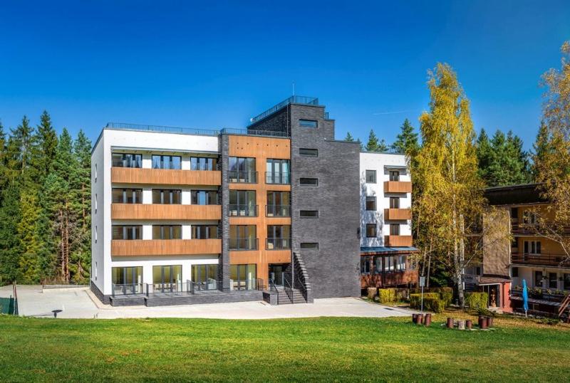 a large building in front of a grass field at Apartman Emma in Liptovský Ján