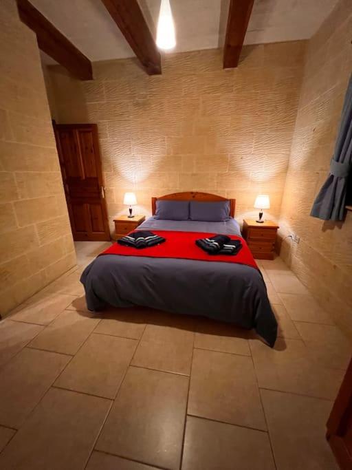 a bedroom with a bed and two lamps on two tables at Ta’ Peppi Farmhouse in Qala