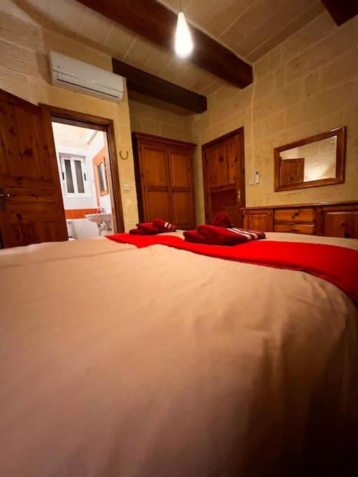 a bedroom with a large white bed with red sheets at Ta’ Peppi Farmhouse in Qala
