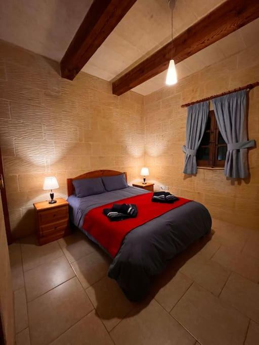 a bedroom with a large red bed with two lamps at Ta’ Peppi Farmhouse in Qala