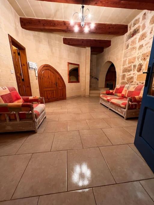 a large room with two chairs and a wooden door at Ta’ Peppi Farmhouse in Qala