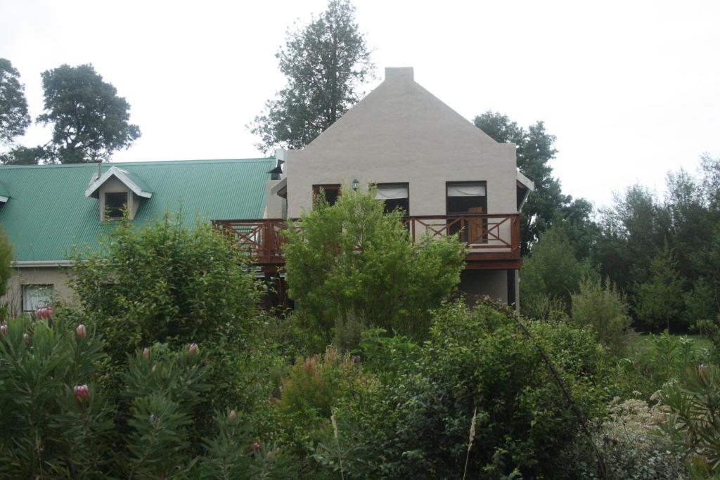 a white house with a deck in the bushes at Fijnbosch Cottage and Camping in Stormsrivier