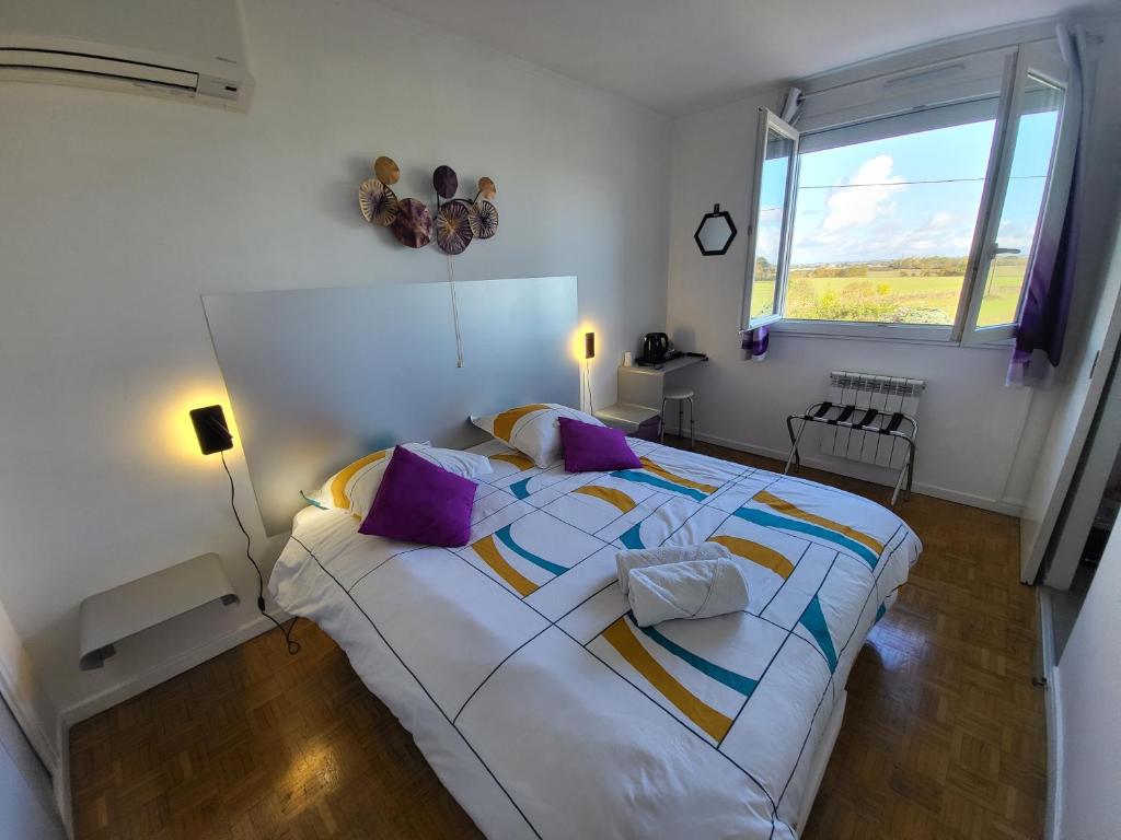 ein Schlafzimmer mit einem großen weißen Bett mit lila Kissen in der Unterkunft Maison VENITIA in Aussonne