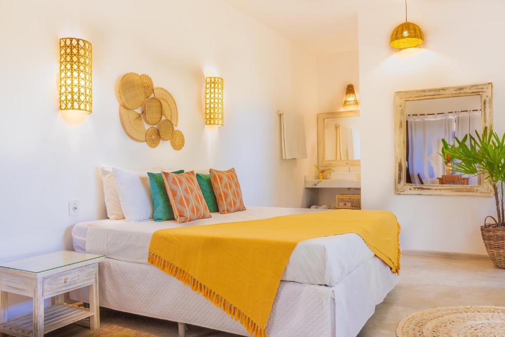 1 dormitorio con 1 cama con manta amarilla en Pariri Suites, en Trancoso
