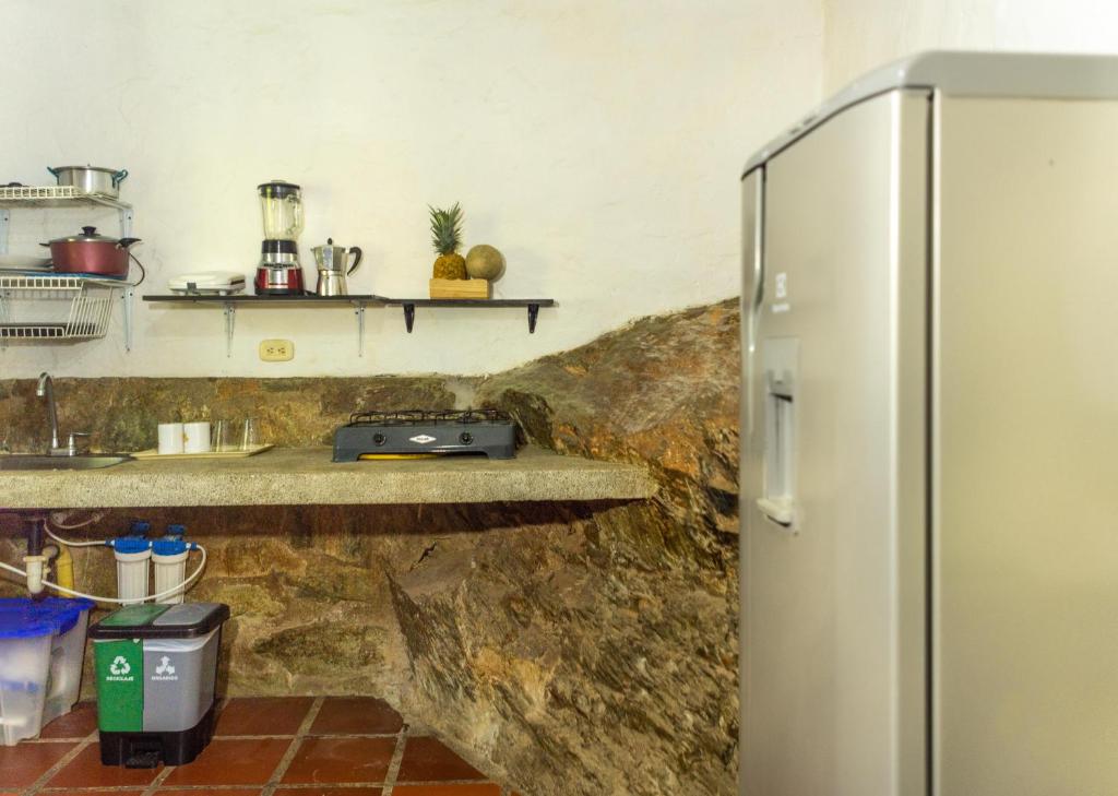 einen Kühlschrank in einer Küche mit einer Steinmauer in der Unterkunft Casa de Piedra Taganga in Taganga