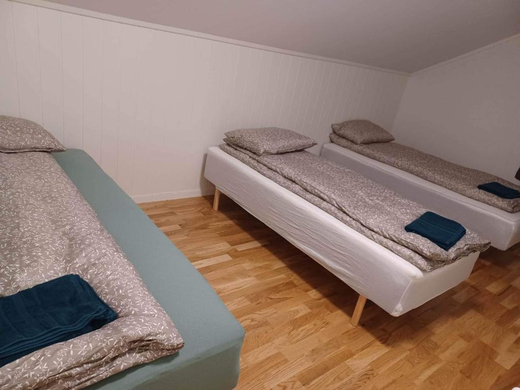 three beds in a room with wooden floors at FeelHome apartment In Tromsdalen in Tromsø