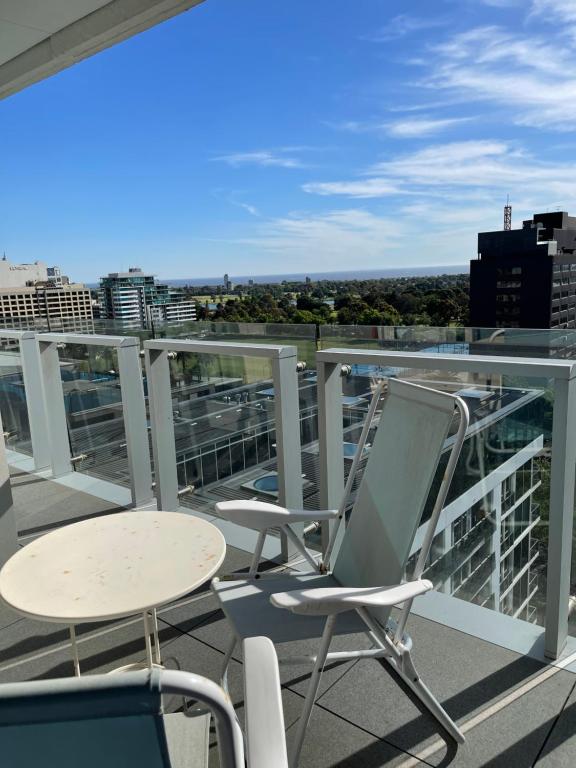 einen Balkon mit Stühlen und Tischen auf einem Gebäude in der Unterkunft The Fawkner Apartment Bay-view pool/Gym Free Parking in Melbourne