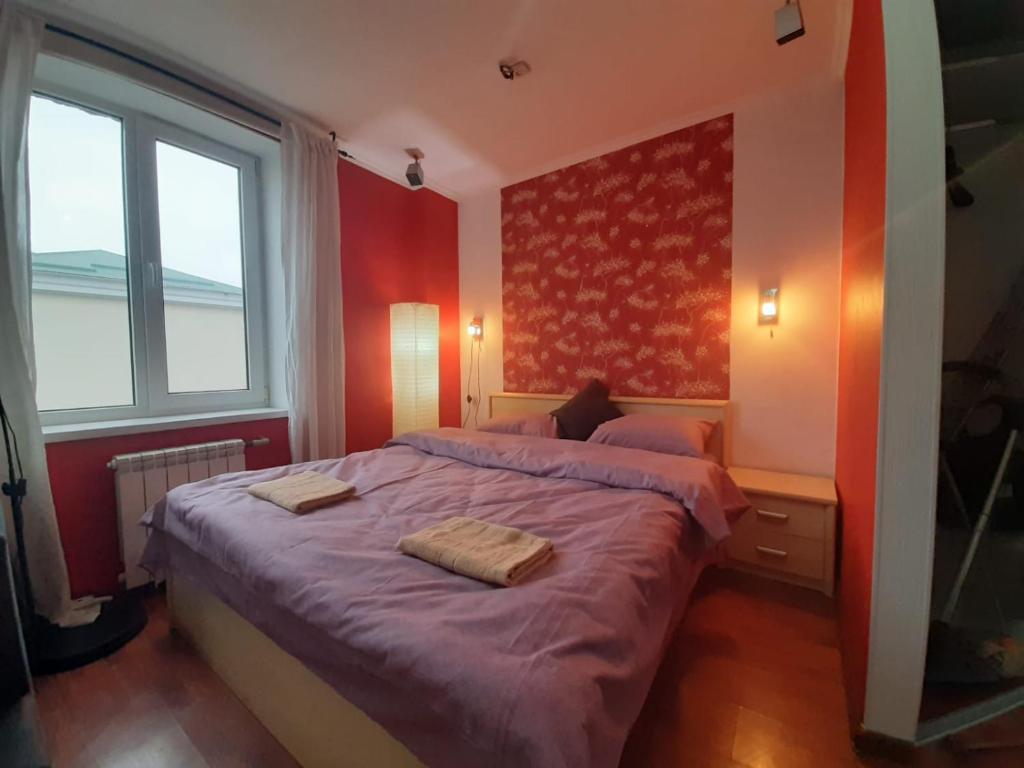 ein Schlafzimmer mit einem Bett mit violetter Bettwäsche und einem Fenster in der Unterkunft Heart Of City Center Flat in Chişinău