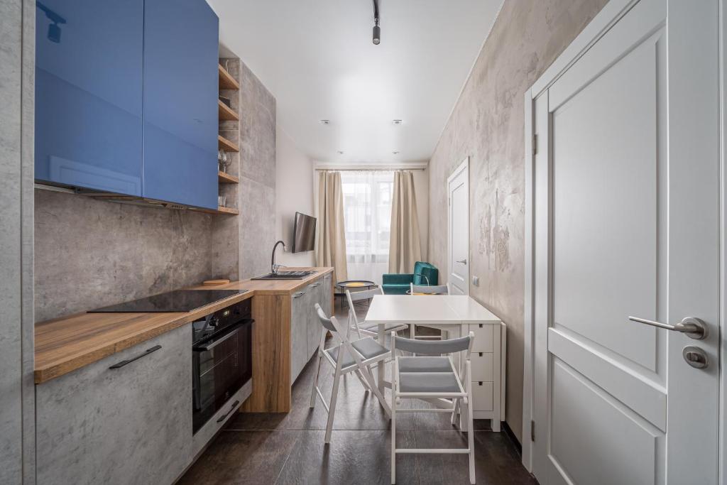 een keuken met blauwe kasten en een tafel en stoelen bij Lovely 1-bedroom apartment with a free parking in Jūrmala