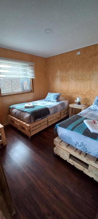 two beds in a room with wooden floors at Cabañas Sierra Dorotea in Puerto Natales