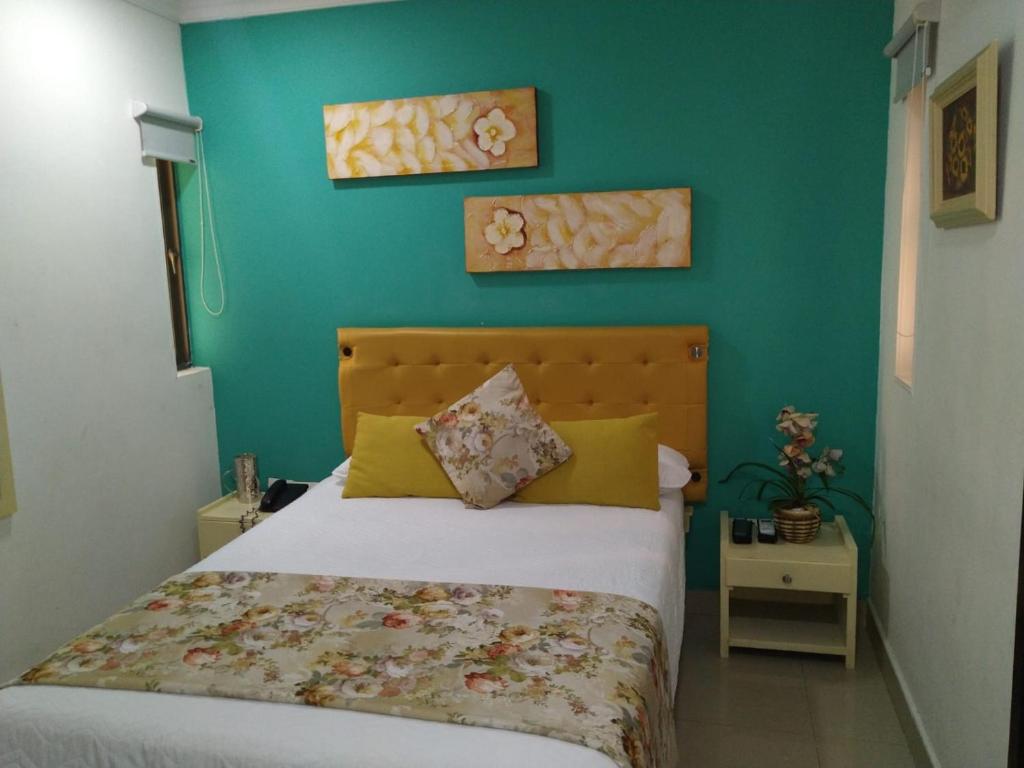モンテリアにあるHotel La Casa Doradaの緑の壁、ベッド付きのベッドルーム1室