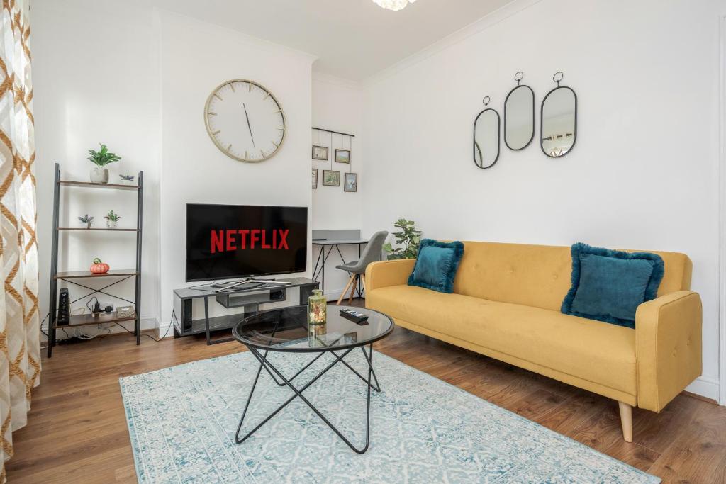 un soggiorno con divano giallo e TV di Entire Lovely family home with Wi-Fi, Netflix, self check-in a Londra