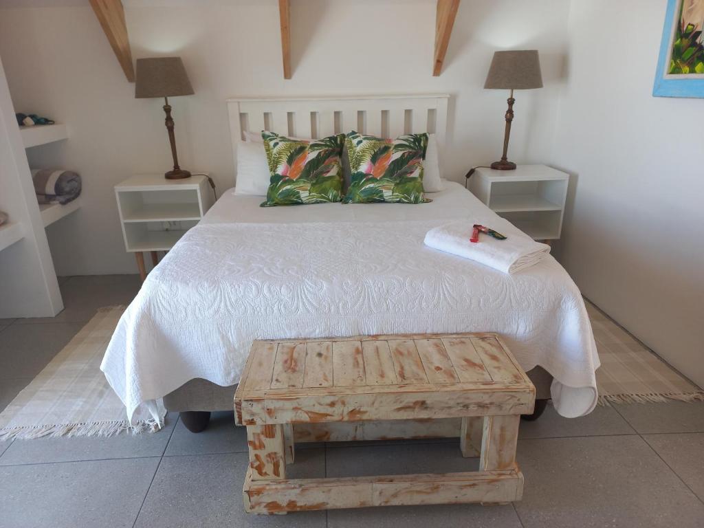 a bedroom with a white bed with a wooden table at CVista in Jacobs Bay