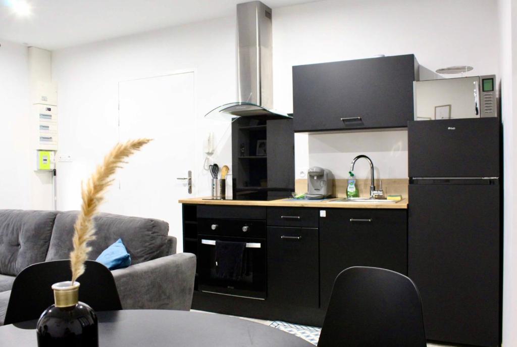 kuchnia z czarną lodówką i stołem w obiekcie Idéal couples & pro - Proche centre ville et gare - Promenade au bord de la Charente - Parking à proximité - Wifi très haut debit - Équipement premium -Netflix w mieście Angoulême