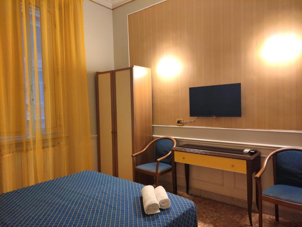 Habitación con cama, escritorio y TV. en Hotel Milazzo Roma en Roma