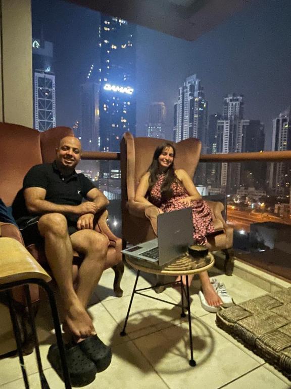 un hombre y una mujer sentados en un balcón con un portátil en Backpackers zone en Dubái
