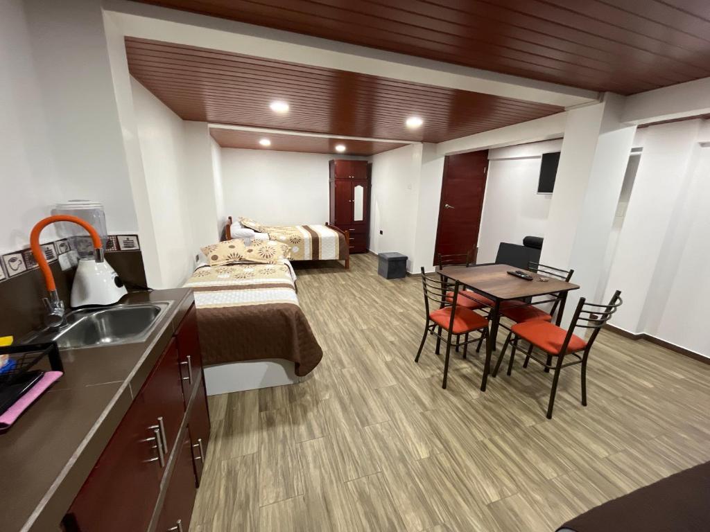 1 dormitorio con 1 cama, mesa y sillas en Bello apartamento en Baños de Agua Santa, en Baños
