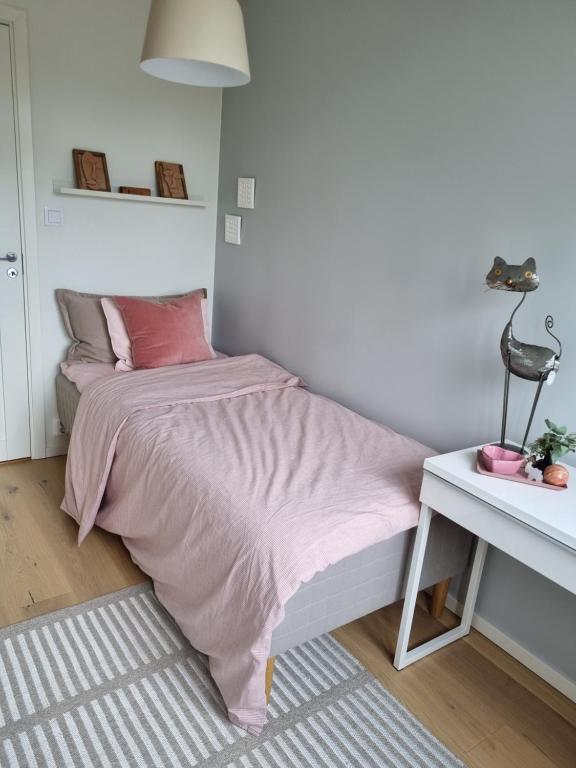 a bedroom with a pink bed and a desk at Welcoming single room in the city center in Gothenburg