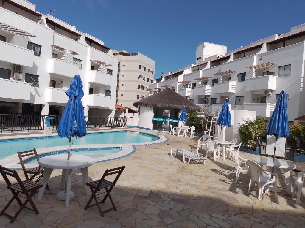 un complejo con piscina, mesas y sillas en Praia Grande- Villa da Praia - Cobertura Duplex!, en Arraial do Cabo