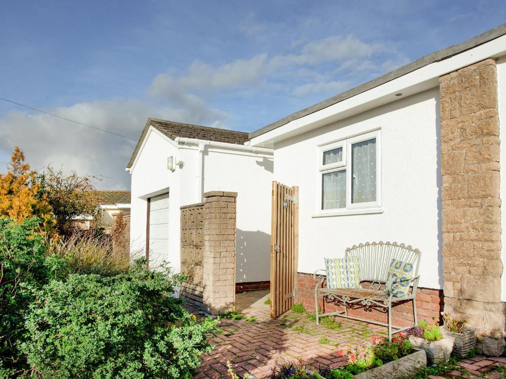 a white house with a chair on a patio at Waterside Park Annexe in Kingsbridge